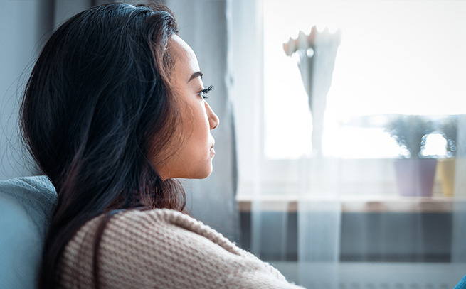 young woman pensively looking out the window