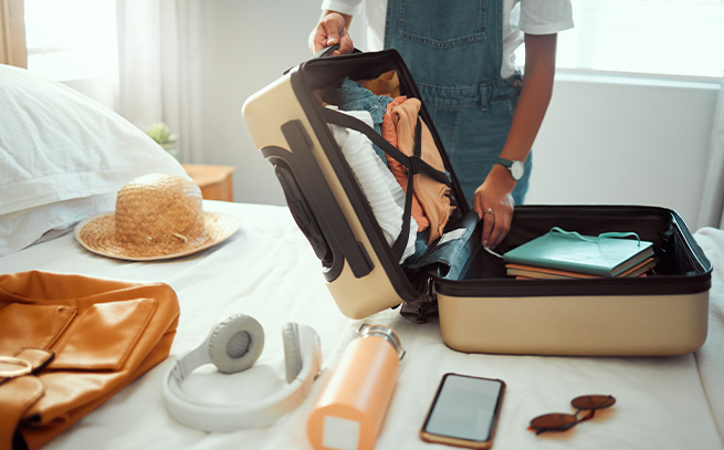 woman packing a suitcase on her bed