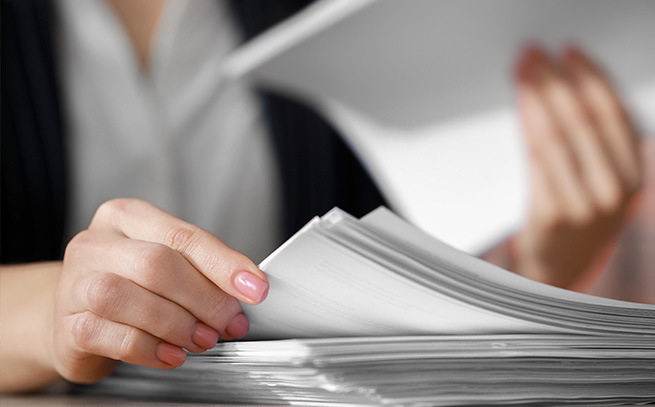 up close shot of a stack of papers and a woman looking through it